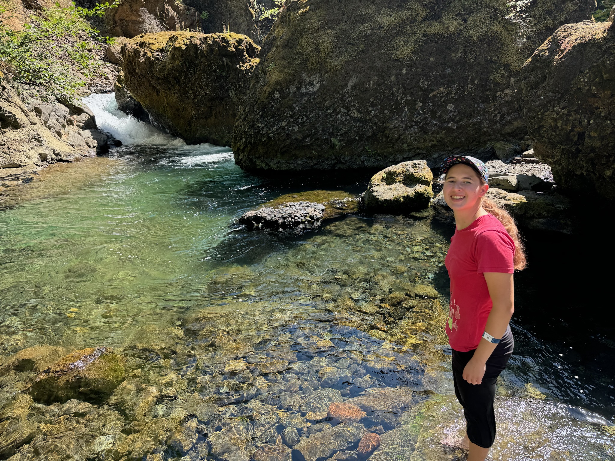 Me standing in a river with a small waterfall in the background